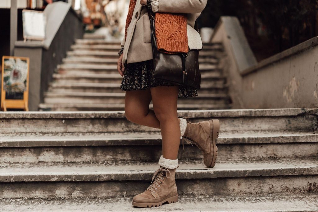 Mujer con botines de gamuza beige en una escalera