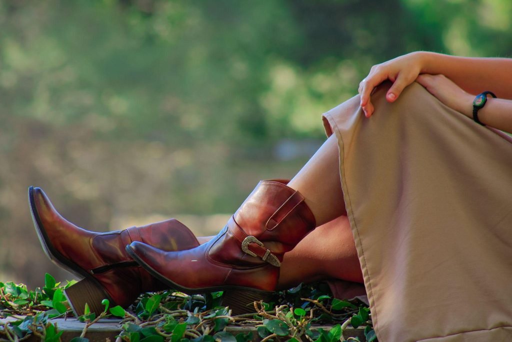 Mujer sentada con botines de cuero marrón al aire libre